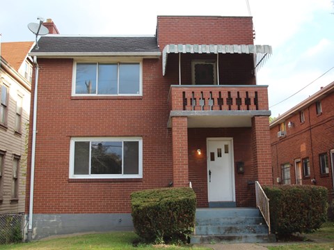 A red brick house with a white door and windows.