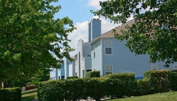 a blue house with trees and bushes in front of it