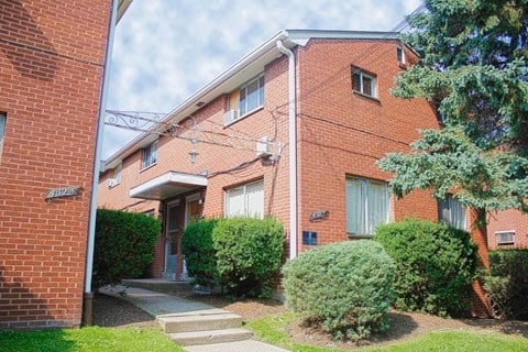 a brick apartment building with stairs and a sidewalk