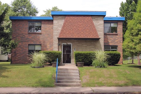 a brick house with a blue roof and stairs