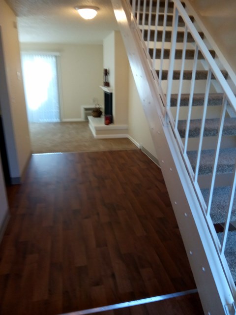 A long hallway with a staircase on the right and a door on the left.