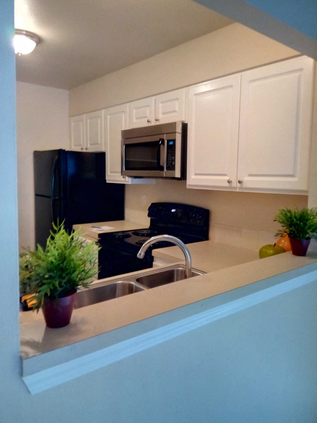 A kitchen with black and white appliances and white cabinets.