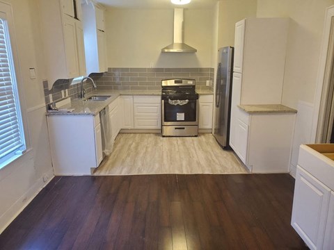 A kitchen with white cabinets and a black stove top oven.