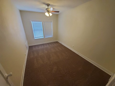 A room with a ceiling fan and a window with blinds.