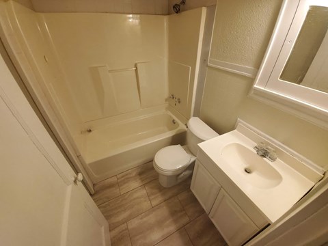 A white bathroom with a toilet, sink, and bathtub.