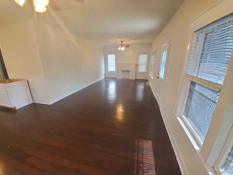 A long, empty room with wood floors and white walls.