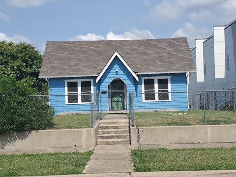 A blue house with a green door and a grey roof.