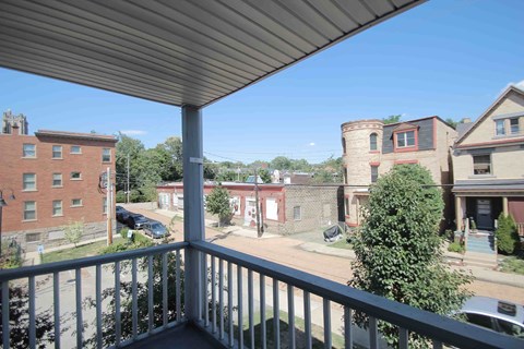 A balcony overlooks a parking lot and buildings.
