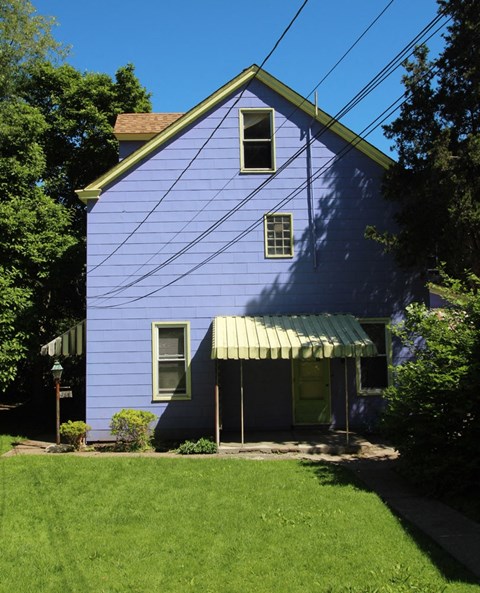 the side of a blue house with a green awning