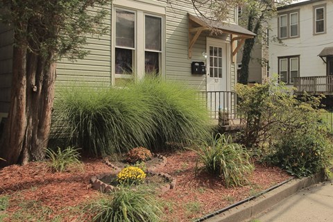 the front yard of a house with a garden and a sidewalk