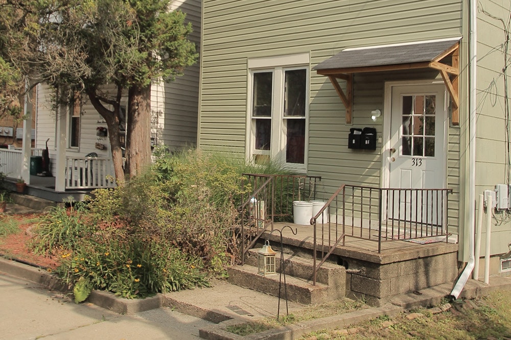 the front of a house with a porch and a white door