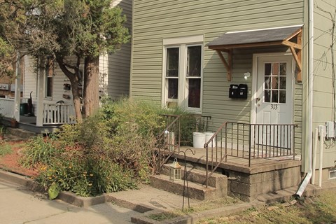 the front of a house with a porch and a white door