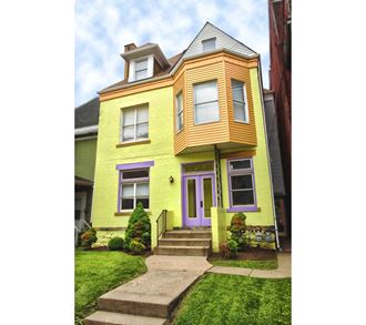 the front of a yellow house with purple and orange trim