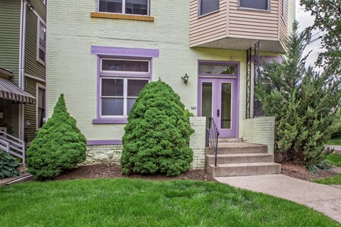 A house with a purple door and a green lawn.