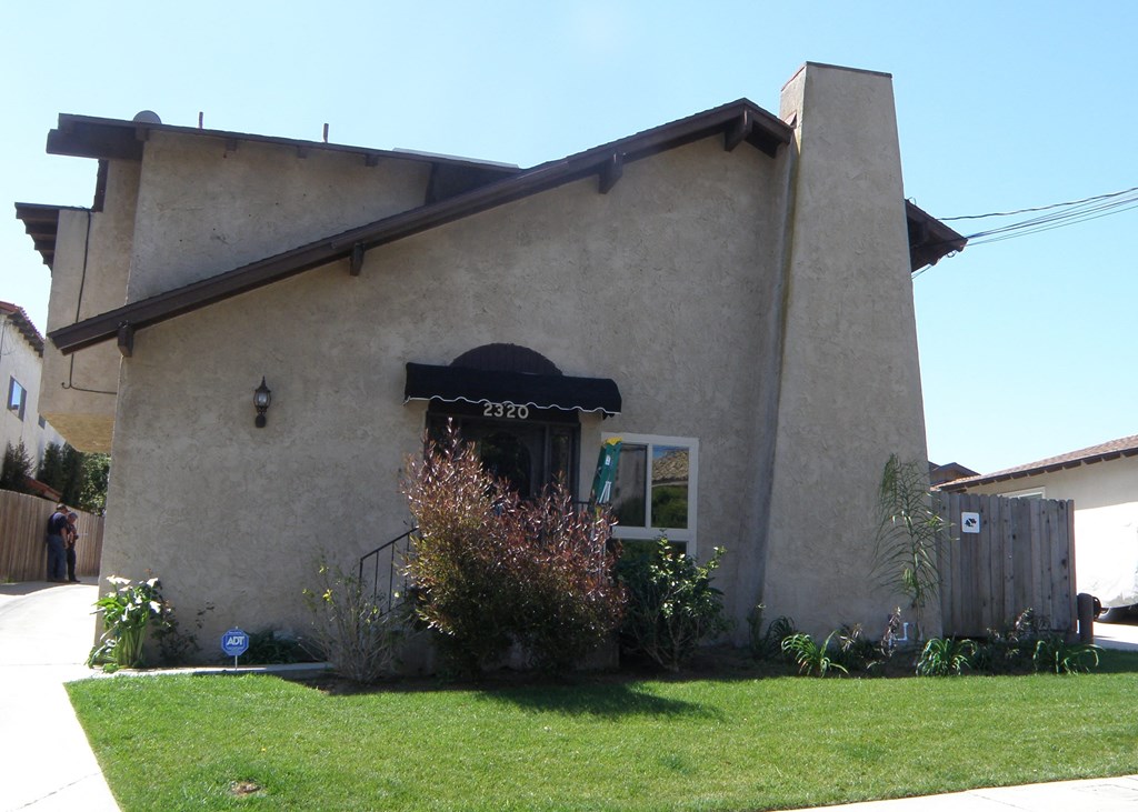 the front of a house with an awning and a lawn