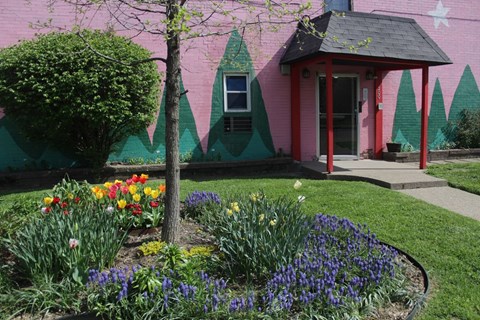 a pink house with a flower garden in front of it