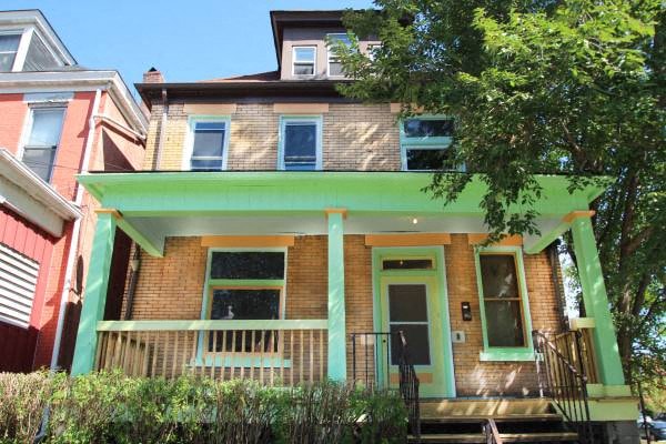 the front of a brick house with a green porch