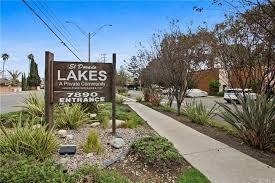 a sign in front of a sidewalk and a parking lot