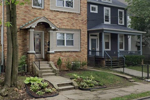 the front of a brick house with steps and a garden