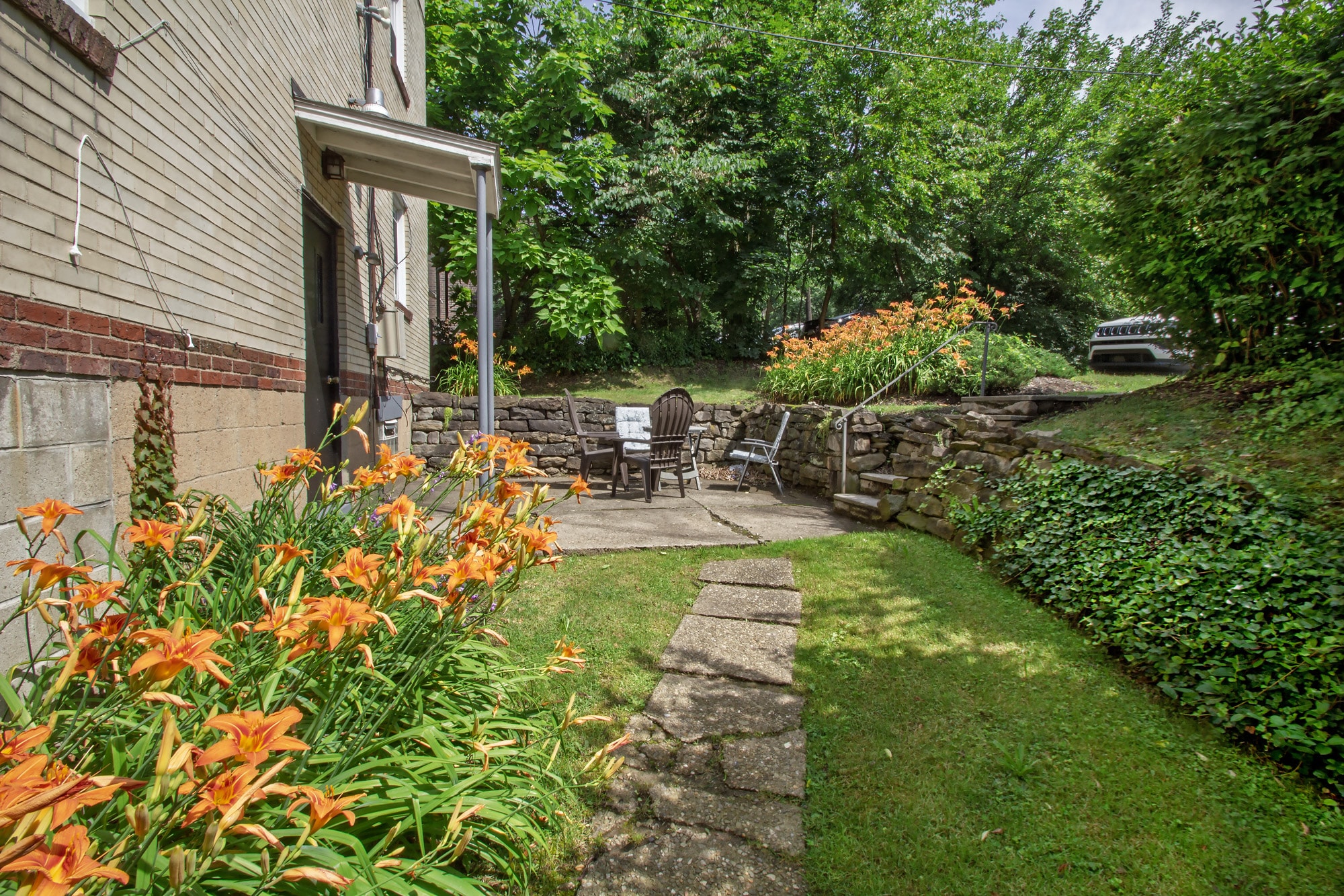 A garden with a stone pathway and orange flowers.