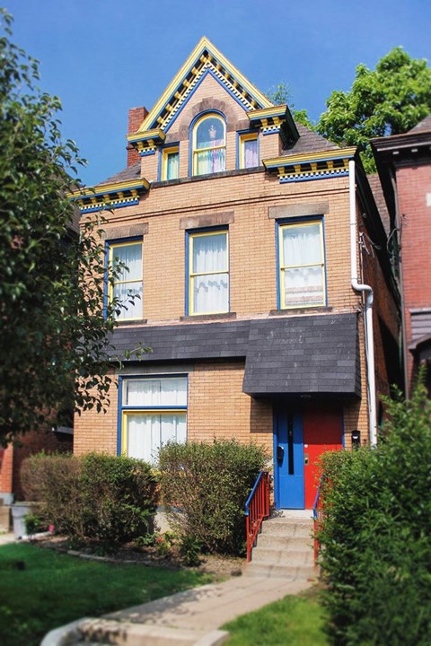 A red brick house with a blue door and a yellow window.