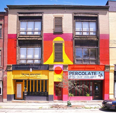 A building with a yellow and red facade has a sign that says "Grand Opening".