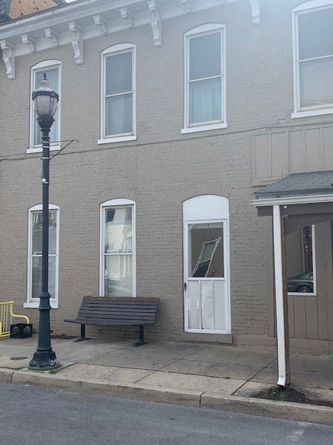 A grey building with a black lamp post and a bench in front of it.