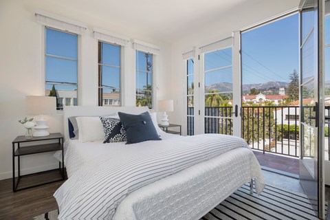 a bedroom with a bed and large windows