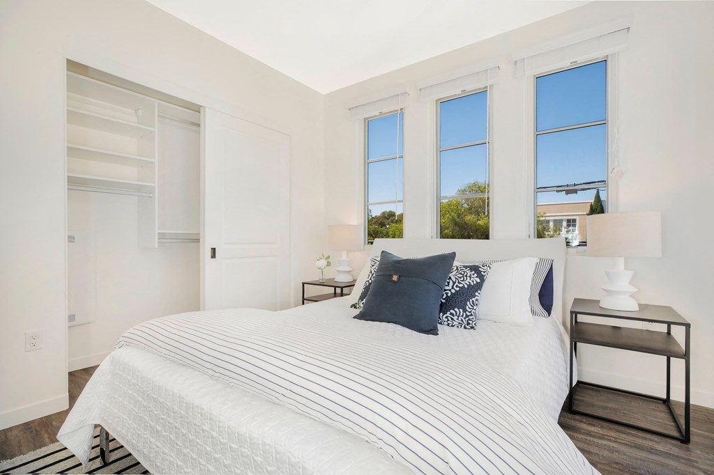 a white bedroom with a large bed and three windows