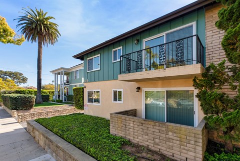 the front of a house with a palm tree next to it