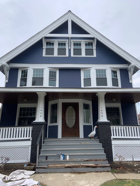 a blue house with a white goose on the front porch