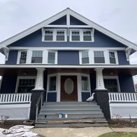 a blue house with a porch and a white fence