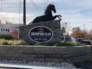 a sign for the champion club with a horse on top of a brick wall