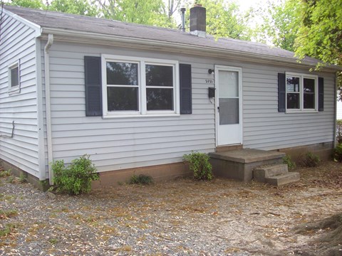 A small house with a grey siding and a white door.