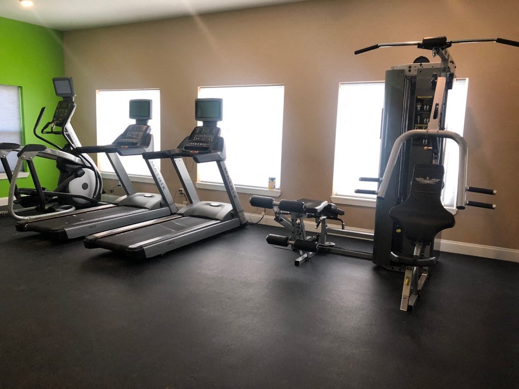 a gym with four ellipticals and weights on the floor