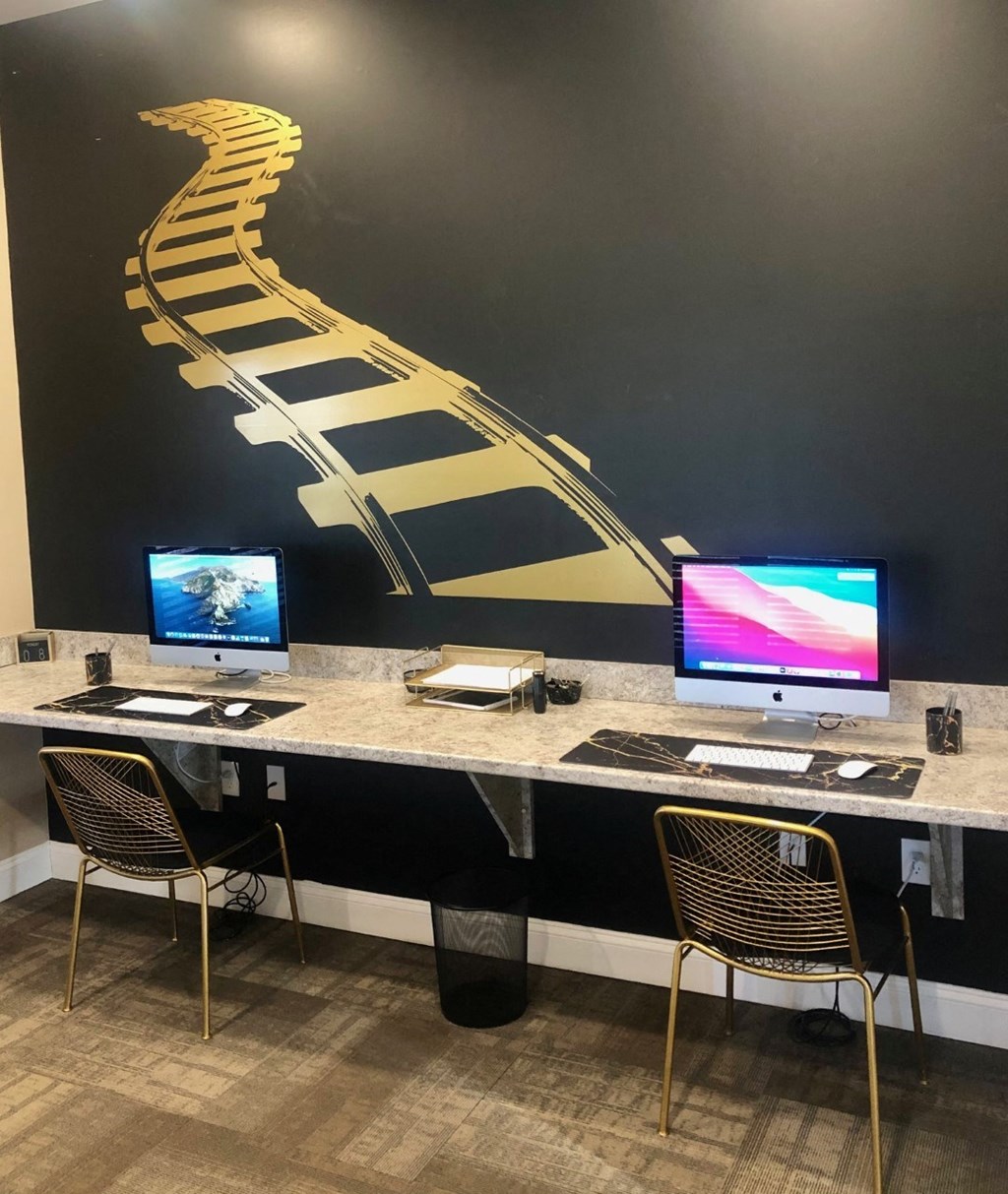a desk with two computers and a mural of a piano on the wall