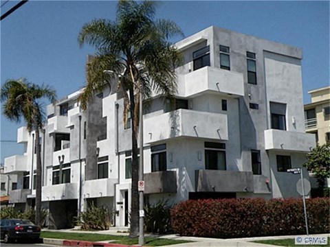 A white building with a black car parked in front.