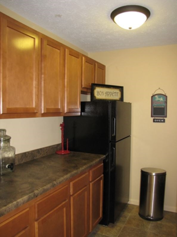 a kitchen with a black refrigerator and wooden cabinets