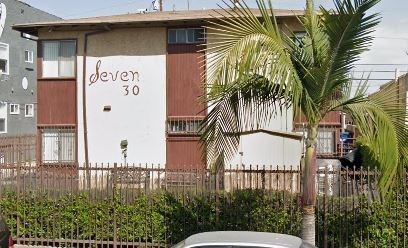 A building with the number 30 on it is surrounded by a fence and a palm tree.