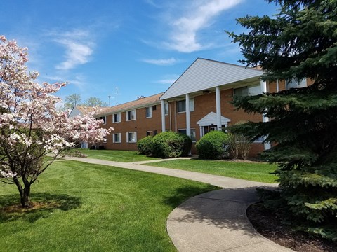 a brick building with a sidewalk and trees in front of it