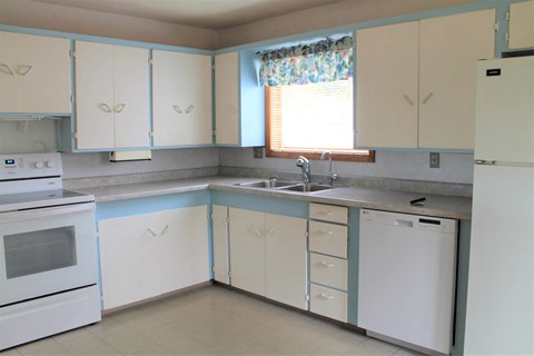 an empty kitchen with white appliances and white cabinets
