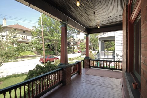 a view of the front porch of a house with a red car on the street