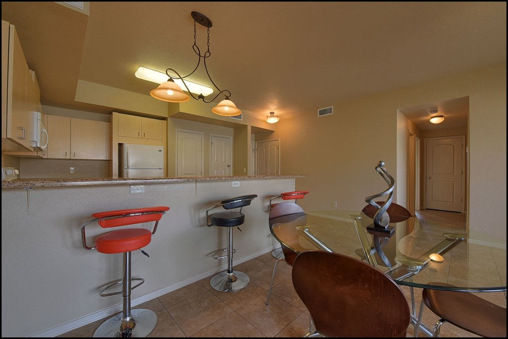 a kitchen with a bar with chairs and a table