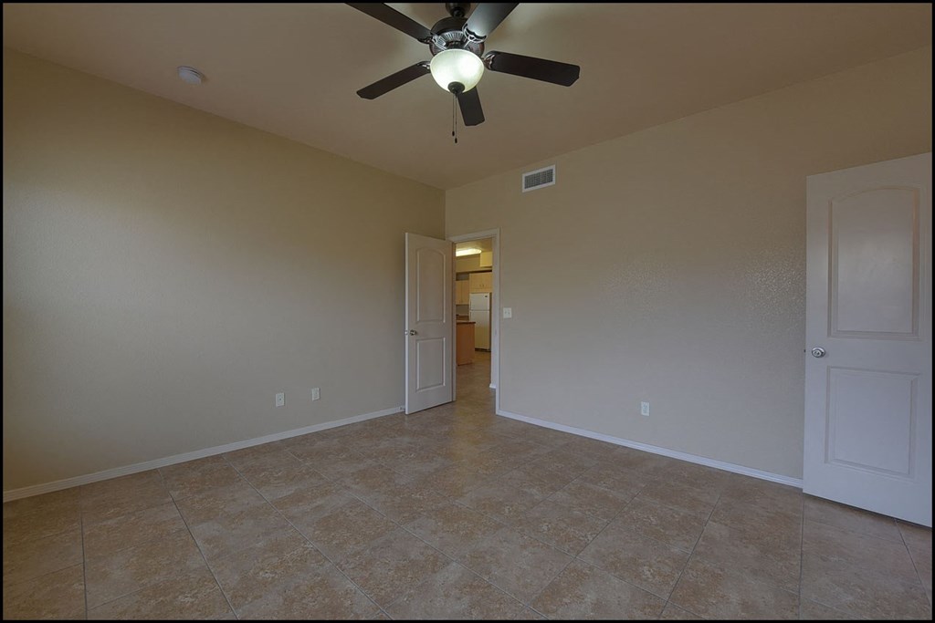 a empty living room with a ceiling fan and tile floor