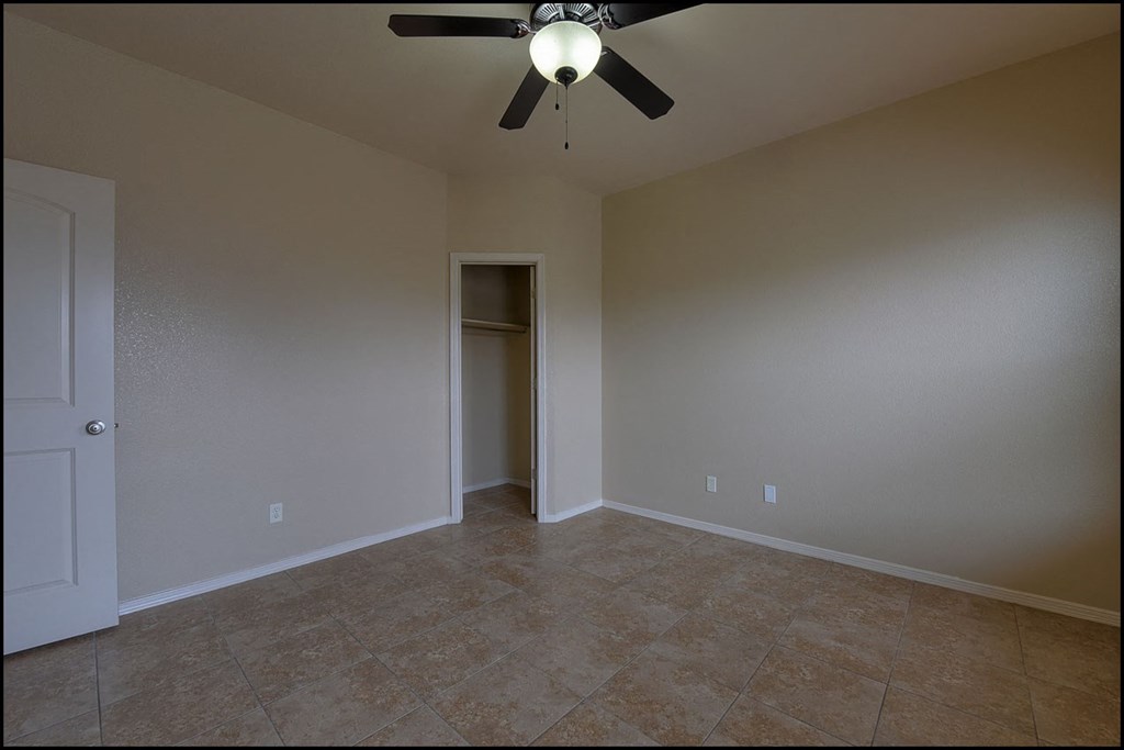 a empty living room with a ceiling fan and tile floor