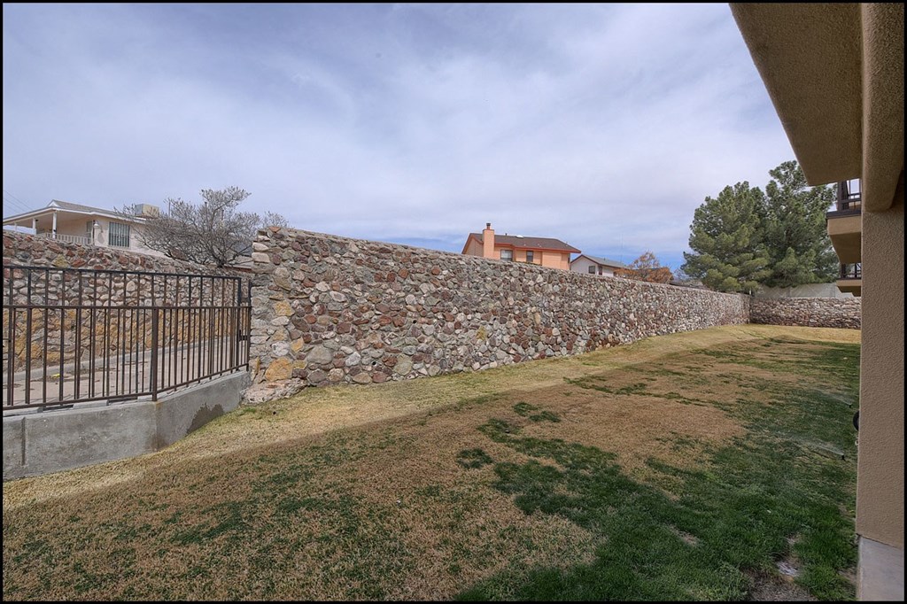 a view of the yard of a house with a stone wall