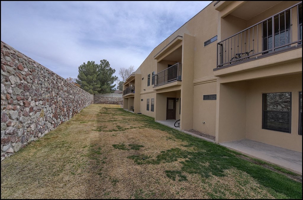 the yard of a house with a stone wall
