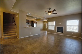 a large empty living room with a ceiling fan