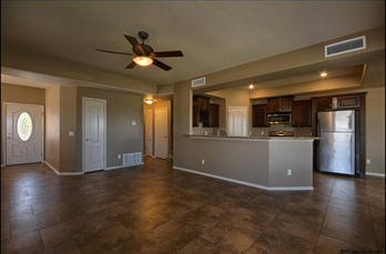 an empty kitchen with a ceiling fan and a refrigerator