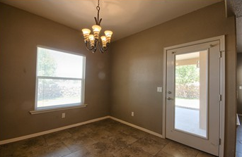 a empty living room with a door and a chandelier